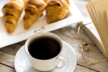 Book and croissants with coffee on the wooden table