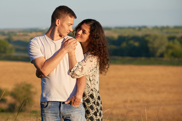 happy young couple posing high on country outdoor over yellow field, romantic people concept, summer season