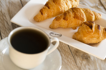 Croissants with coffee on the wooden table
