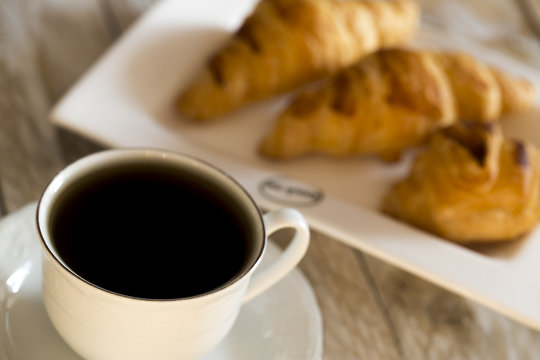Croissants with coffee on the wooden table