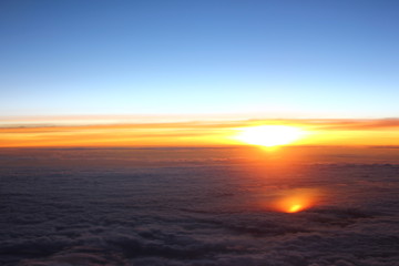 Fototapeta na wymiar Sunrise above clouds from an airplane