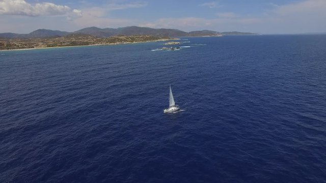 Aerial view of sailing yacht boat moving in blue sea water / Drone flying over boat