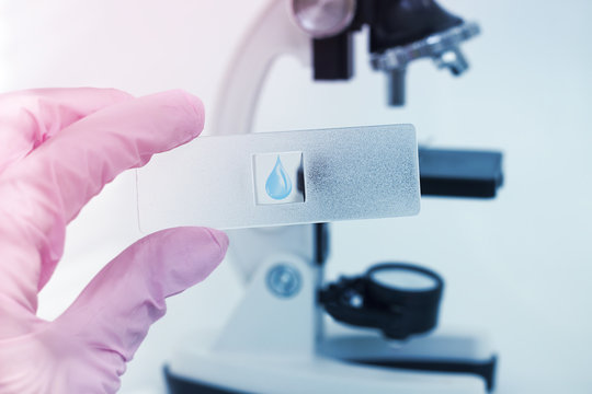 Close-up of scientist in a laboratory microscope with microscope slide in