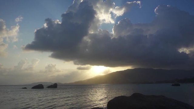 Sunbeams Breaking Through the Clouds at Sunset over the Mountain near the Sea. Slow Motion