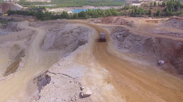 Aerial view of magnesite mine/ Drone flying over the mine and follows heavy truck