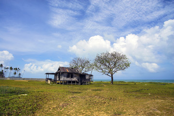 Old abandoned house under blue sky near the beach.