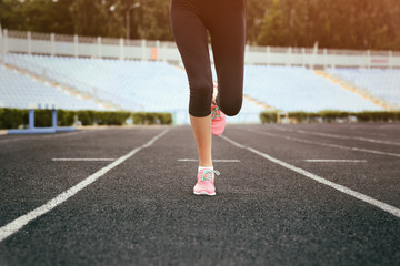 Woman running in pink sneakers on a stadium