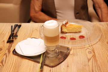 Latte and piece of tasty dessert for man in restaurant