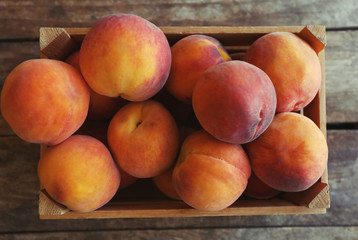 Fototapeta na wymiar Fresh peaches in a box on a wooden background