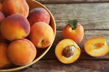 Fresh peaches in a bowl on a wooden background