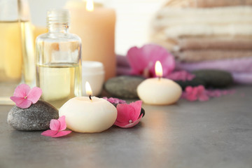 Spa composition with candle and flowers on table, closeup