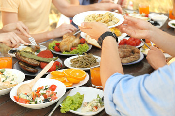 Friends passing plate with potato on picnic