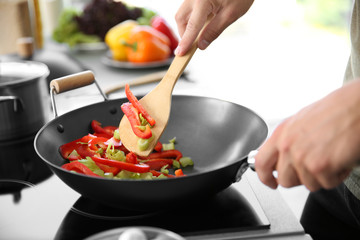 Male hand mixing vegetables in pan closeup