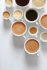 Cups of coffee on white background, top view