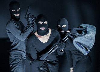 Armed thieves in balaclavas on black background