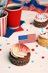 Delicious cupcake with flag decoration and drink on white wooden background