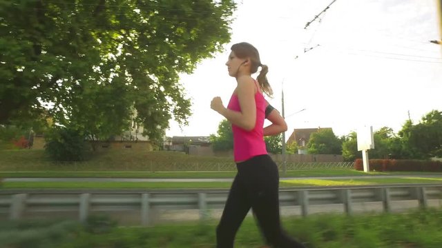 Runner woman running in city exercising outdoors.  Sportswoman wearing fitness tracker bracelet and listening to music while training in the city.