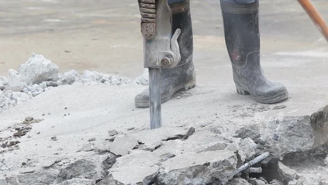 Construction worker removes excess concrete with drilling machine