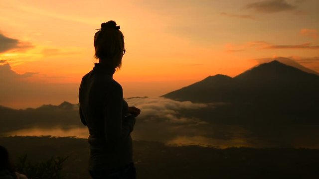 Girl watching sunrise over Lake Batur, Volcano Agung and Abang, Bali, Indonesia