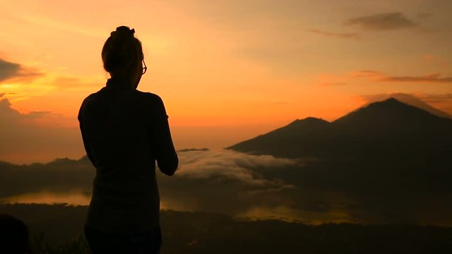 Girl taking pictures of sunrise over Lake Batur, Volcano Agung and Abang, Bali