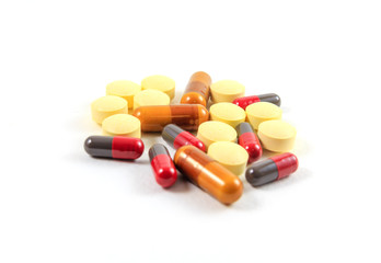 Close up shot of pile of assorted pills, tablets and drugs on white background.