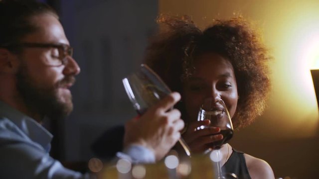 Young Couple Toasting Wine Glass In Luxury bar. Dating. Hipster and black woman on romantic dinner drinking at bar
