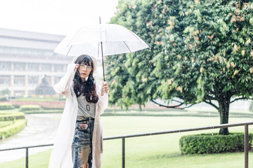 Charming Asian girl  with umbrella and raincoat