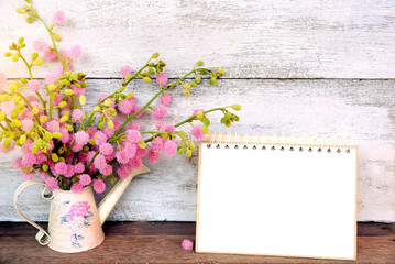  blank notebook page and pink spring flower on white wooden wall background 