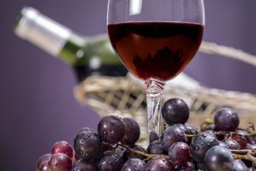 Close-up of red wine glass surrounded by grapes, in front of Rioja wine bottle