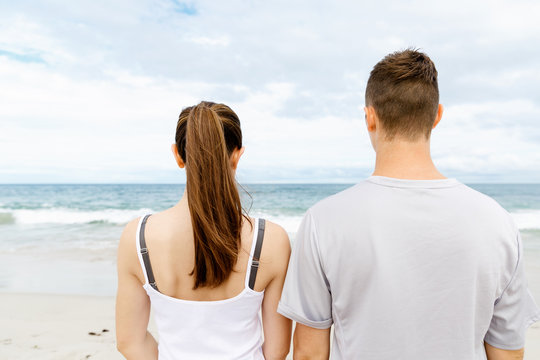 Young couple looking thoughtful while standing next to each other on beach