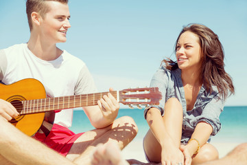 Beautiful young people with guitar on beach