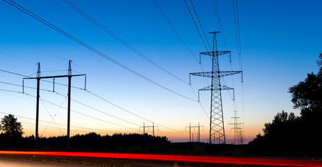 Pylons and electricity power lines at night with traffic lights