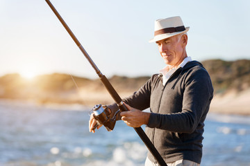Senior man fishing at sea side