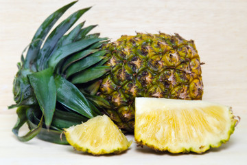 Fresh pineapple with slices isolated on wood