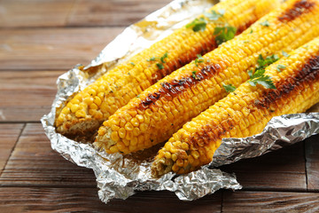 Tasty grilled corn on brown wooden table