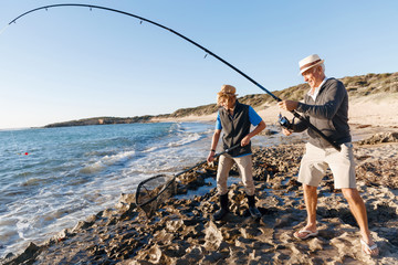 Senior man fishing with his grandson