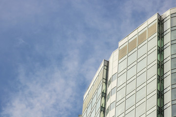 The glass facade of a skyscraper with a mirror reflection of sky windows