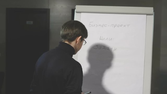 Young man making a presentation about the flip-chart.