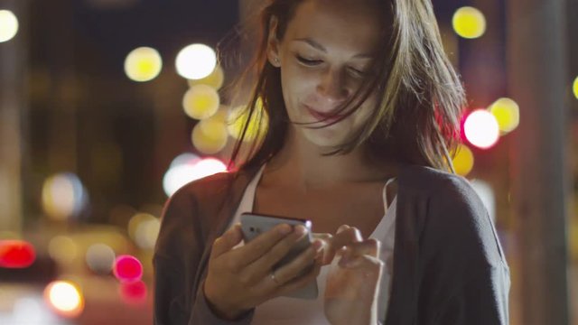 Attractive Woman using Mobile Phone During Walk on Streets of Night Town. Shot on RED Cinema Camera in 4K (UHD).