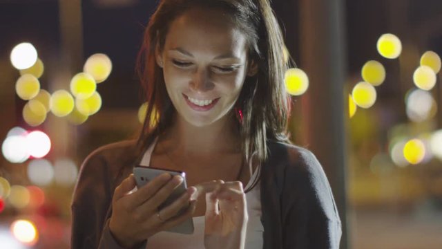 Attractive Woman using Mobile Phone During Walk on Streets of Night Town. Shot on RED Cinema Camera in 4K (UHD).