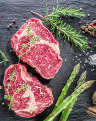 Rib eye steak with spices on the black background.