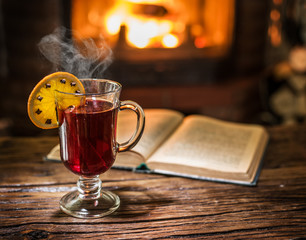 Hot mulled wine and a book on the wooden table.