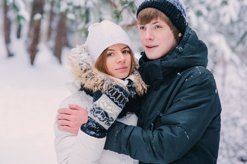 Fototapeta premium young happy couple walking in winter snowy forest, wearing warm knitted gloves with christmas ornament