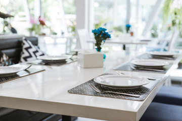 Modern white table in dining room with elegant table setting, selective focus, shallow depth of field