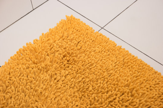 Soft yellow carpet lies on a white tile.