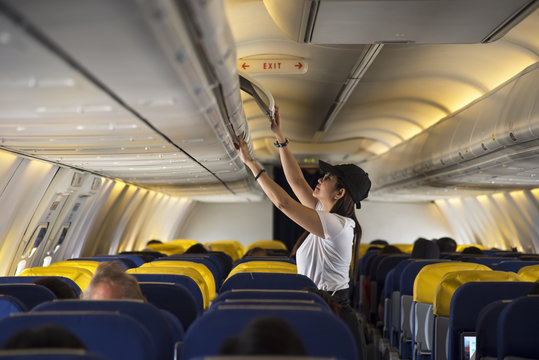 Traveller woman open overhead locker on airplane
