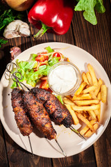 Grilled shish kebab served with fried chips and salad
