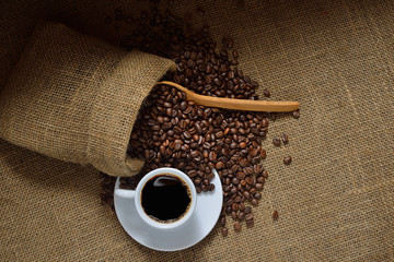 Top view of cup of coffee and coffee beans on burlap background