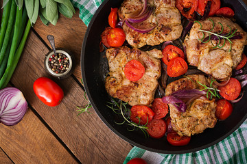 Juicy pork steak with rosemary and tomatoes on pan. Top view