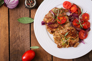Juicy pork steak with rosemary and tomatoes on a white plate. Top view